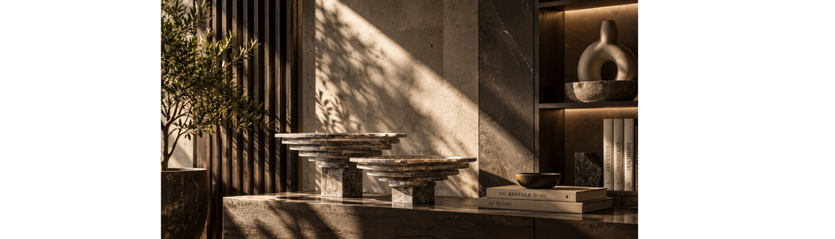 Travertine sculptural decor objects styled on a dark console in a warm minimalist interior with natural light