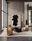 Modern living room with beige armchairs, a black coffee table, and abstract art on the wall.