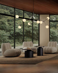 Modern living room with large windows, beige chairs, and a chandelier.
