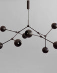Modern black chandelier against a gray background from 101 Copenhagen available at Spacio retail stores in Mumbai & Kolkata.