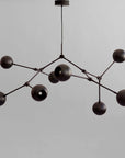Modern black chandelier with multiple spherical lights on a gray background from 101 Copenhagen available at Spacio retail stores in Mumbai & Kolkata.