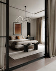 Modern bedroom with a bed, side table, and abstract light fixture.