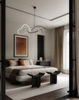 Modern bedroom with a bed, side table, and abstract light fixture.