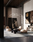 Modern living room with abstract art, stylish furniture, and a hanging light fixture.