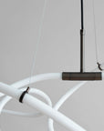 Modern chandelier with white curved arms and a dark metal fixture on a neutral background