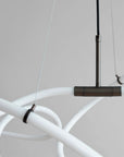 Modern chandelier with white curved arms and a dark metal fixture on a neutral background