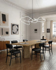 Modern dining room with wooden table and black chairs, featuring a stylish chandelier.