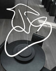 Neon light sculpture of a hand on a wooden floor