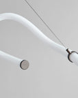 Close-up of a modern ceiling light fixture with white arm and metallic base.