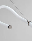 Close-up of a modern ceiling light fixture with white arm and metallic base.