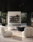 Modern Japandi theme living room with white armchairs, a round black coffee table, and bookshelves.