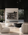 Modern Japandi theme living room with white armchairs, a round black coffee table, and bookshelves.