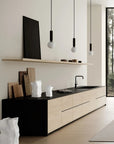 Modern kitchen with black and white cabinetry, wooden flooring, and a large window.