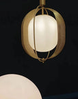 Pendant light with gold frame and white glass shade on a black background
