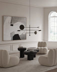 Modern living room with beige chairs, black coffee table, and abstract art on the wall.