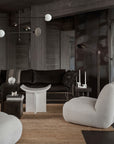 Modern living room with dark leather sofa, gray armchair, and minimal decor.