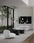 Modern living room with white furniture, black coffee tables, and abstract art on the wall.