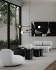Modern living room with white furniture, black coffee tables, and abstract art on the wall.