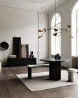 Modern interior design with a black round table, white bench, and decorative light fixture.
