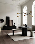 Modern interior design with a black round table, white bench, and decorative light fixture.