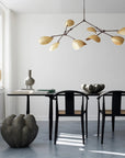 Modern dining room with black table and chairs, decorative vases, and a chandelier.