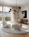 Modern living room with white furniture, round rug, and large windows.