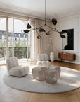 Modern living room with white furniture, round rug, and large windows.