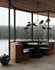 Modern interior with a round table and bench seating by large windows with a view of water and trees.