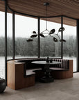 Modern interior with a round table and bench seating by large windows with a view of water and trees.