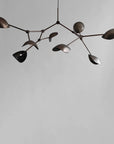 Modern chandelier with leaf-like design in bronze finish on a plain background from 101 Copenhagen available at Spacio retail stores in Mumbai & Kolkata.