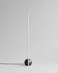 Modern floor lamp with a black base and white cylindrical shade on a light gray background