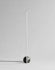 Modern floor lamp with a black base and white cylindrical shade on a light gray background