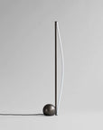 Minimalist floor lamp with a spherical base on a plain background