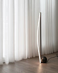 Modern floor lamp against a white curtain backdrop