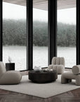 Modern living room with gray furniture and large windows overlooking a lake.