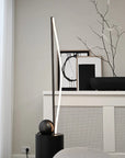 Modern interior design with a black floor lamp and decorative items on a white surface.