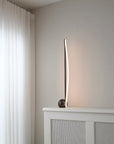 Modern floor lamp on a white radiator with white curtains in the background