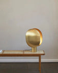 Brass table lamp on a wooden table against a plain wall