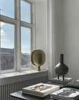 Modern interior with a window, books, and a minimal sculptural vase on a table.