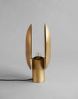 Side view of a brass table lamp with unique design on a gray background, from 101 Copenhagen available at Spacio retail stores in Mumbai & Kolkata.