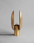 Side view of a brass table lamp with unique design on a gray background, from 101 Copenhagen available at Spacio retail stores in Mumbai & Kolkata.