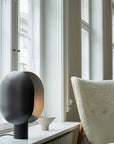 Modern black and gold spherical lamp on a windowsill with a neutral background