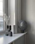 Gray decorative objects on a windowsill with a view of a building outside.
