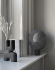 Gray decorative objects on a windowsill with a view of a building outside.