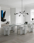 Modern dining room with a glass table and white chairs in a minimalistic setting.