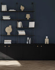 Black shelving unit with decorative items against a dark blue wall