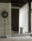 Modern interior with concrete wall, floor lamp, and white curtain.