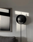 Modern black floor lamp in a minimalistic room with abstract art on the wall.