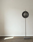Modern floor lamp with a round metallic shade on a neutral background