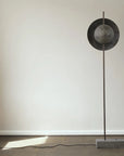 Modern floor lamp with a round metallic shade on a neutral background